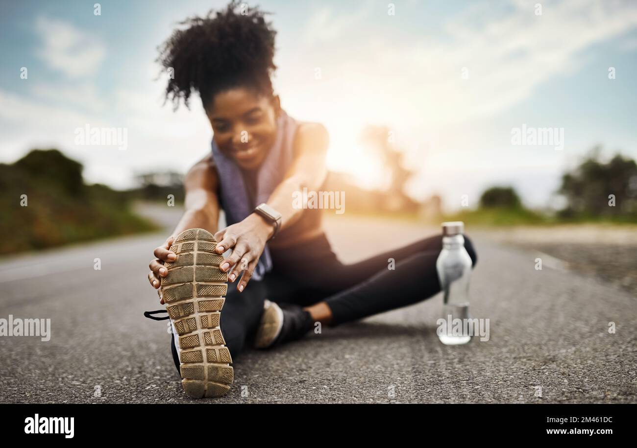 Sie hat ihre Warm-Up-Routine überstanden. Eine sportliche junge Frau, die sich beim Sport im Freien die Beine ausstreckt. Stockfoto