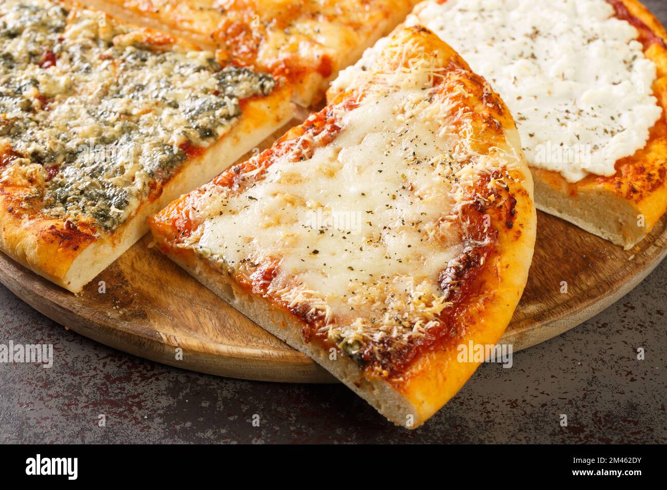 Pizza Quattro formaggi oder vier Käsesorten mit Tomatensoße, Parmesan, Mozzarella, Gorgonzola, Ricotta, als Nahaufnahme auf dem Holzbrett auf dem Tisch. Horizont Stockfoto