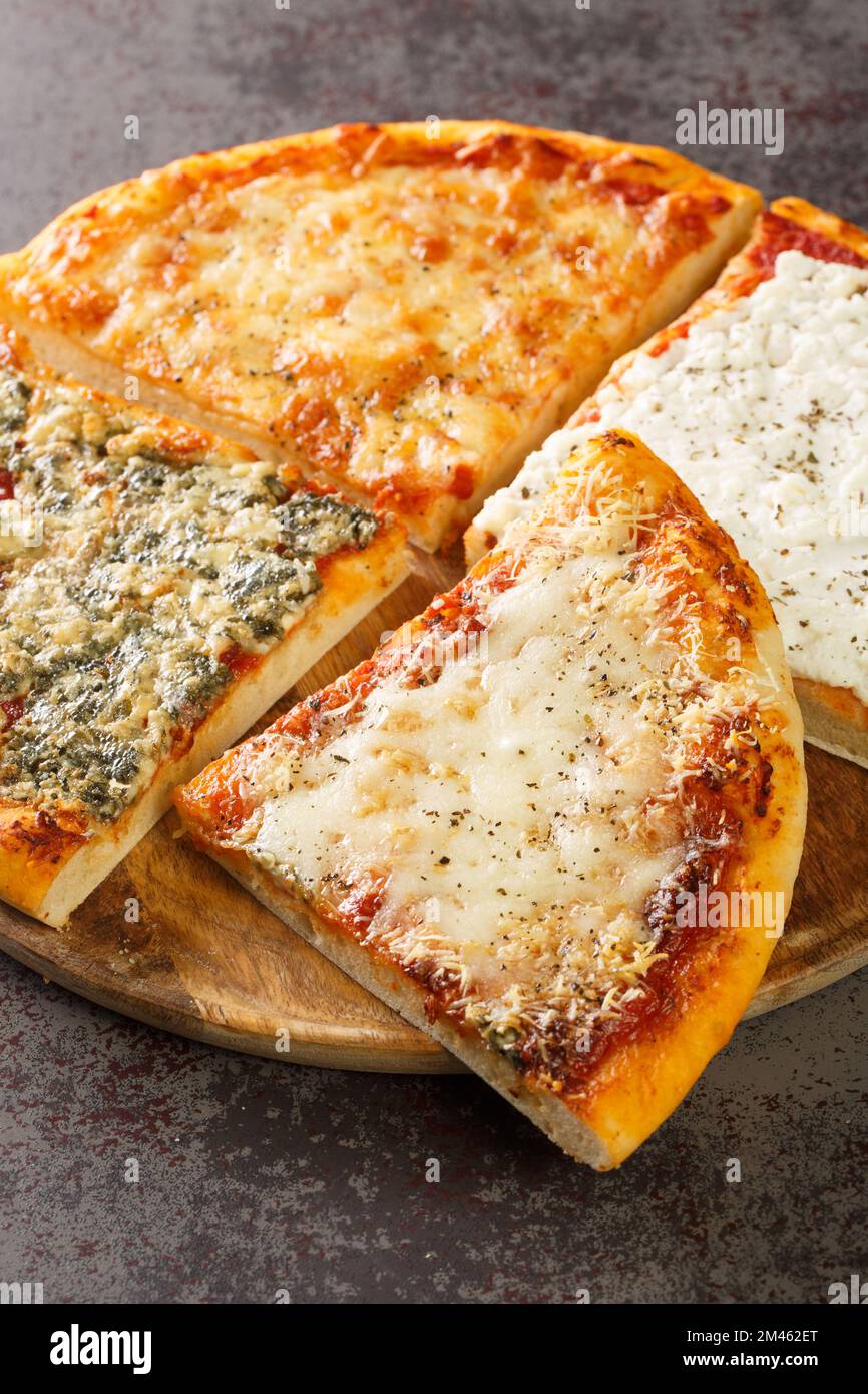 Geschnittene heiße Pizza, vier Käsesorten aus der Nähe auf einem Holzbrett auf dem Tisch. Vertikal Stockfoto