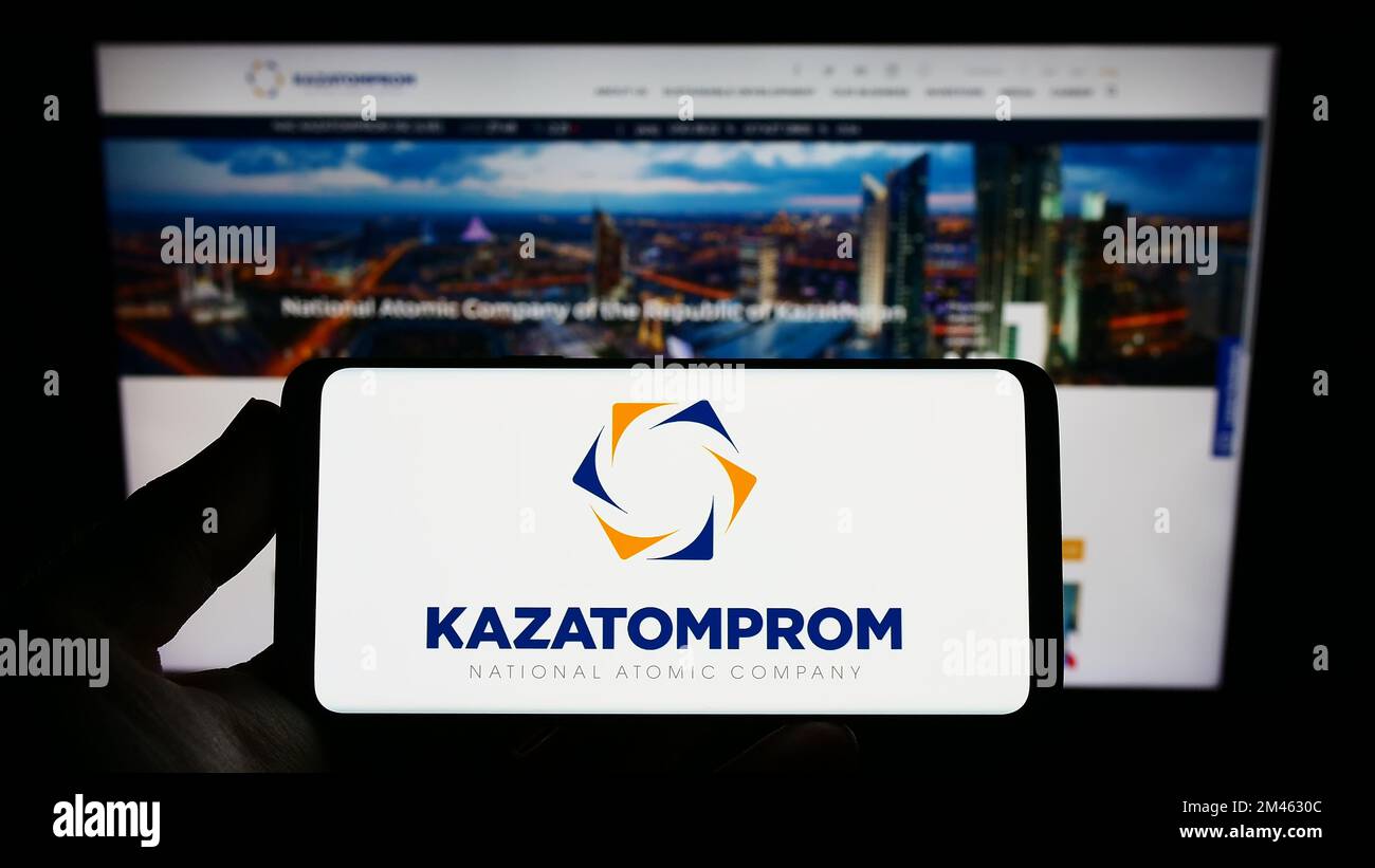 Person, die ein Smartphone mit dem Logo des kasachischen Uranbergbauunternehmens Kazatomprom auf dem Bildschirm vor der Website hält. Konzentrieren Sie sich auf das Display des Telefons. Stockfoto