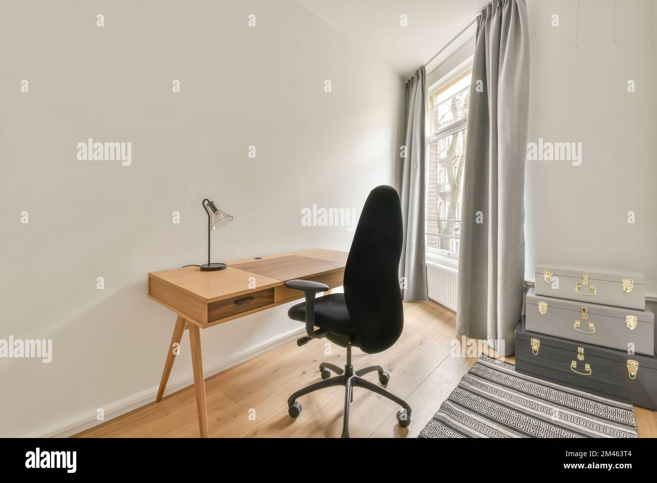 Ein kleiner Arbeitsbereich mit Holztisch und ergonomischem Stuhl neben dem Fenster Stockfoto