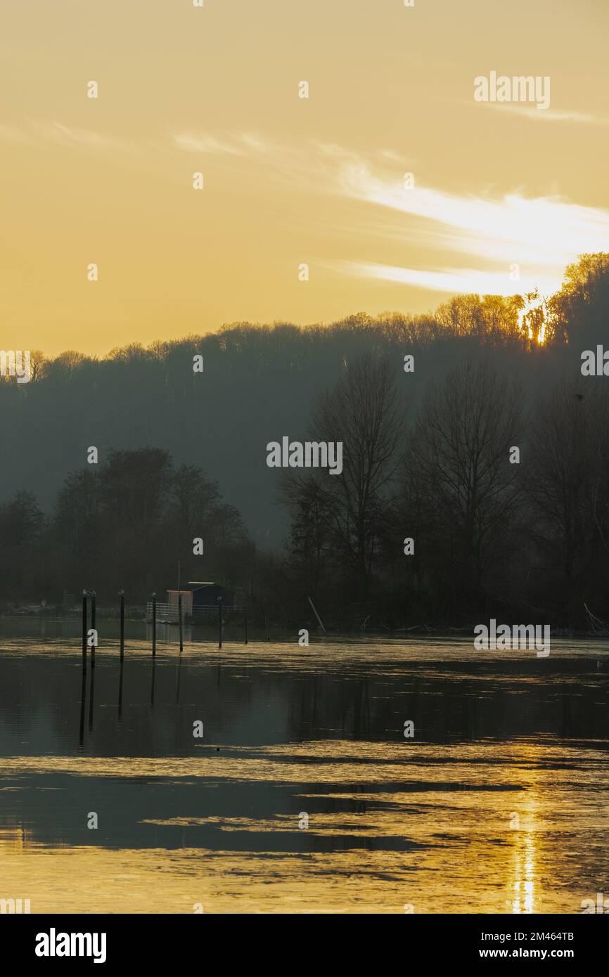 Ein nebeliger Abend während eines atemberaubenden farbenfrohen Sonnenuntergangs mit Reflexionen über dem Pietersplas-Teich in Maastricht, der eine magische und geheimnisvolle Atmosphäre schafft Stockfoto