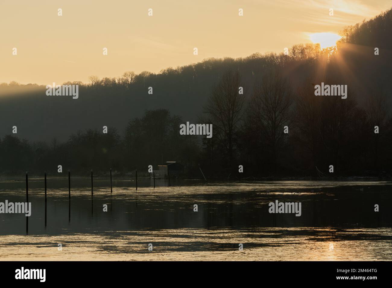 Ein nebeliger Abend während eines atemberaubenden farbenfrohen Sonnenuntergangs mit Reflexionen über dem Pietersplas-Teich in Maastricht, der eine magische und geheimnisvolle Atmosphäre schafft Stockfoto