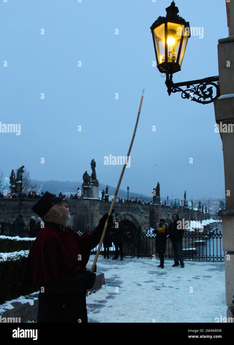 Der Lampenanzünder beleuchtet traditionelle Gaslampen auf der Karlsbrücke im Zentrum von Prag, Tschechische Republik, 18. Dezember 2022. (CTK Photo/Milos Rum Stockfoto