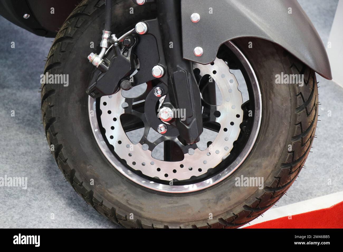 Scheibenbremsen für elektrische Roller in modernem Design am Vorderrad mit Blick auf Aluminiumfelge und Stoßdämpfer Stockfoto