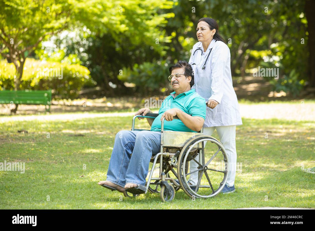 Indische Pflegekraft, die sich um ältere männliche Patienten im Rollstuhl draußen im Park kümmert, asiatischer Arzt hilft und unterstützt ältere ältere Menschen. Stockfoto