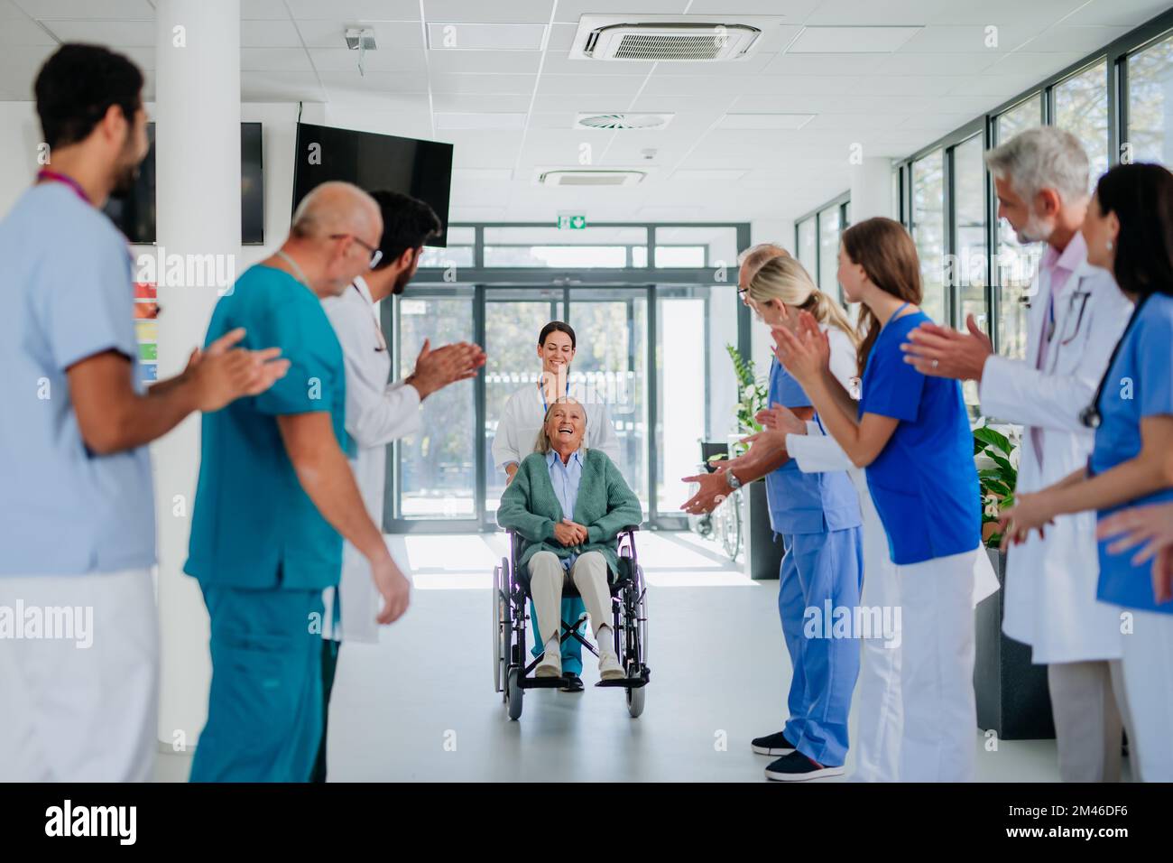 Medizinisches Personal klatscht zu Seniorpatienten, die sich von einer schweren Erkrankung erholt haben. Stockfoto