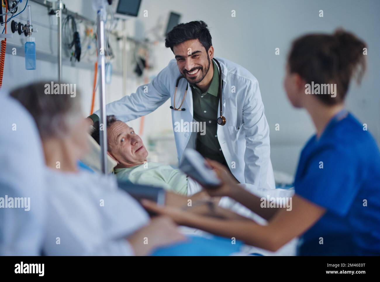 Junger Arzt aus dem Nahen Osten, der während der Untersuchung von Patienten im Krankenzimmer lächelt. Stockfoto