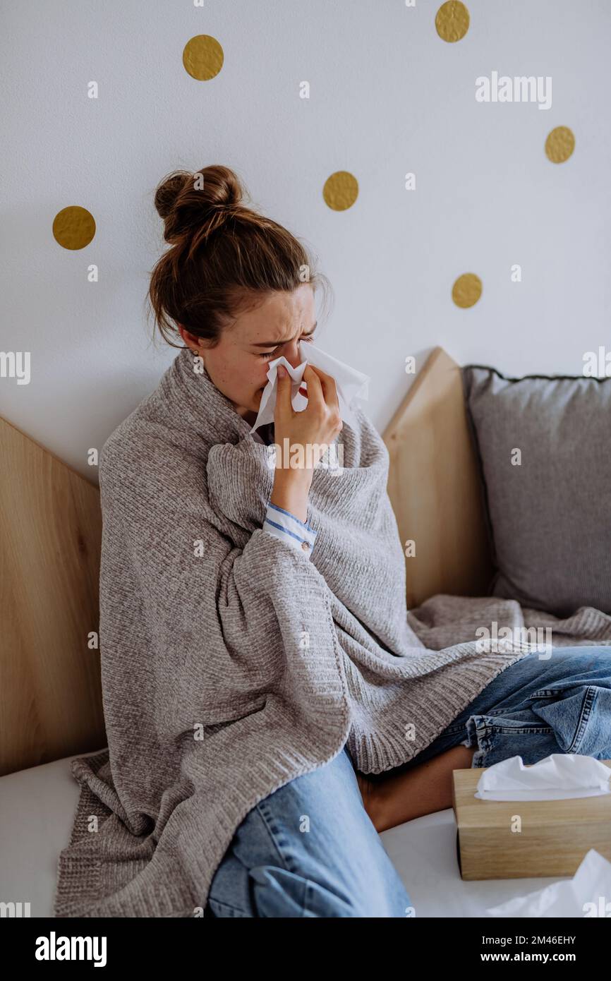 Eine kranke Frau, die im Bett sitzt und erkältet ist. Stockfoto