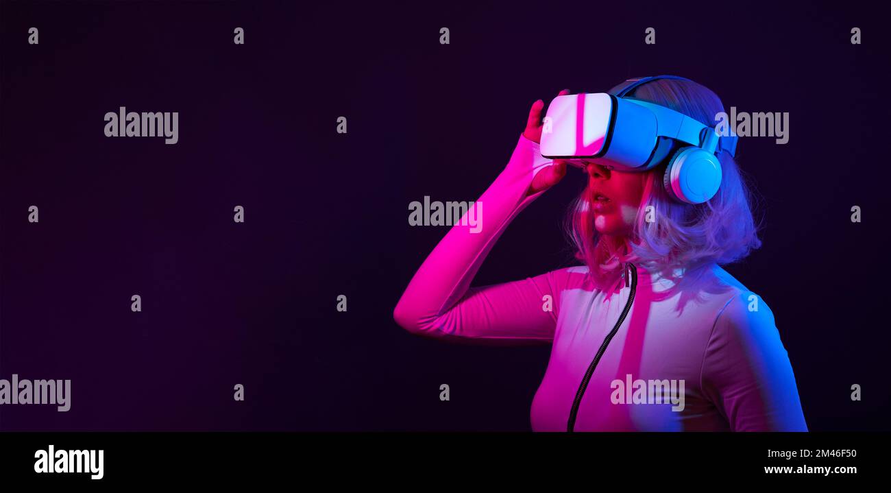 Eine Frau in Virtual-Reality-Brille in Neonfarben. Das Konzept der digitalen Technologie für Metaversum und Unterhaltung der Zukunft. Stockfoto