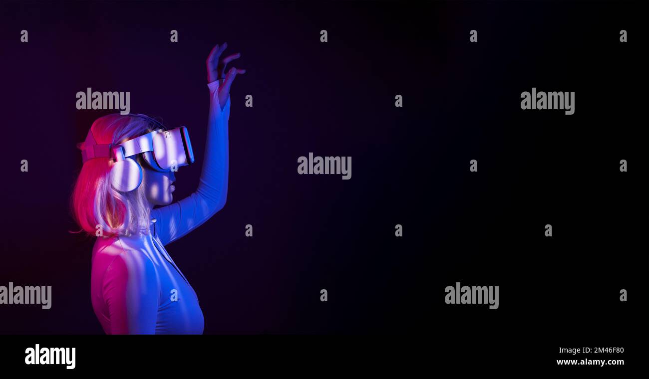 Eine Frau in Virtual-Reality-Brille in Neonfarben. Das Konzept der digitalen Technologie für Metaversum und Unterhaltung der Zukunft. Stockfoto