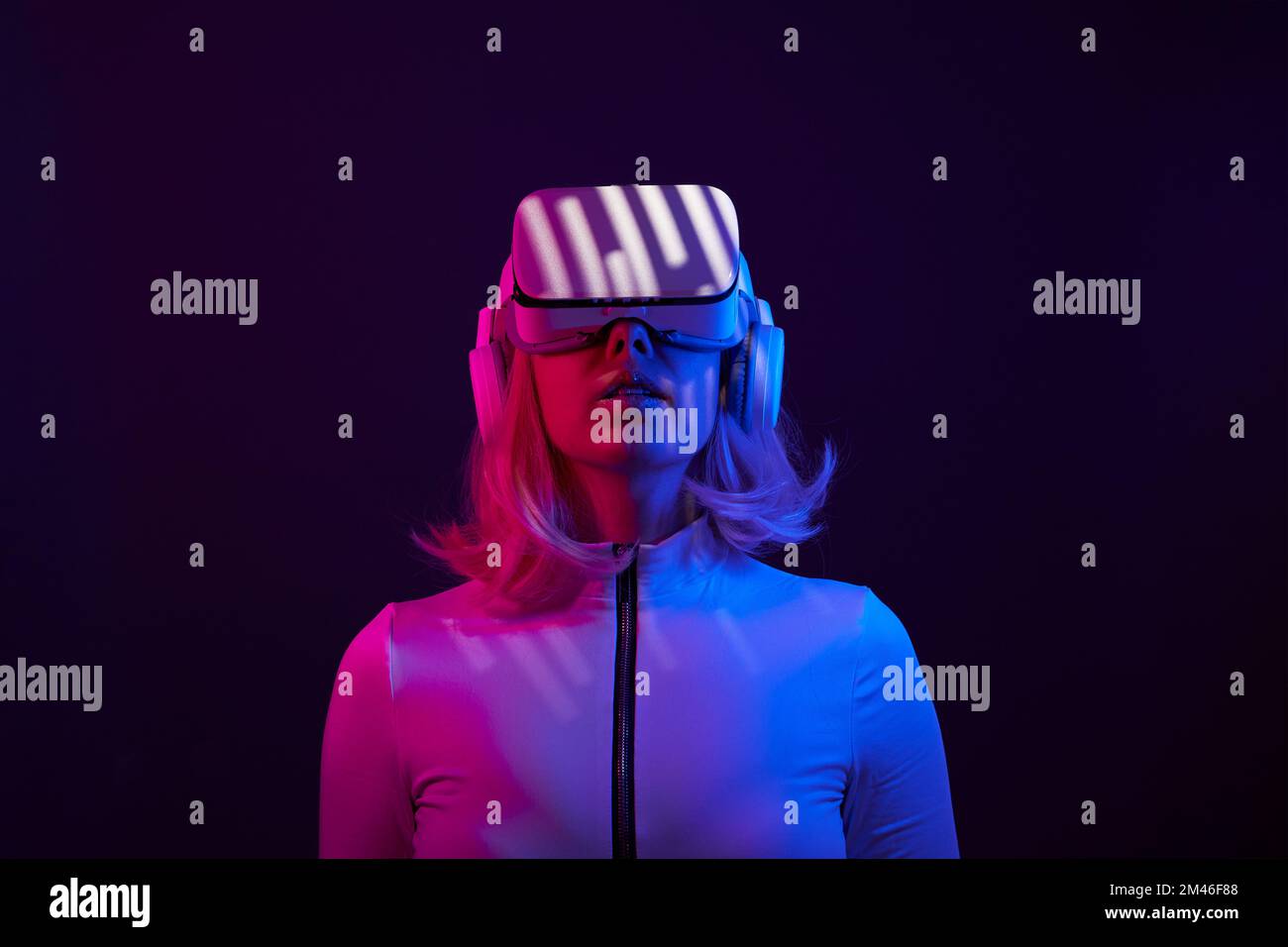 Eine Frau in Virtual-Reality-Brille in Neonfarben. Das Konzept der digitalen Technologie für Metaversum und Unterhaltung der Zukunft. Stockfoto