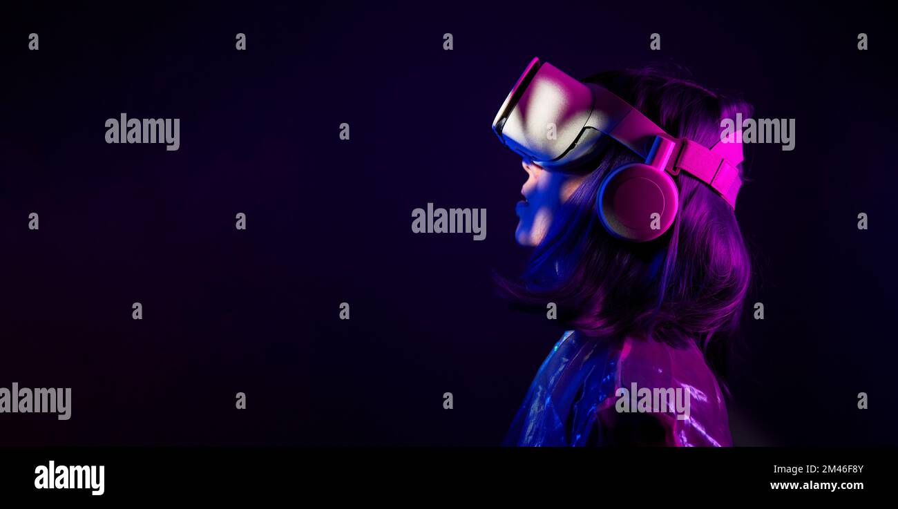 Eine Frau in Virtual-Reality-Brille in Neonfarben. Das Konzept der digitalen Technologie für Metaversum und Unterhaltung der Zukunft. Stockfoto