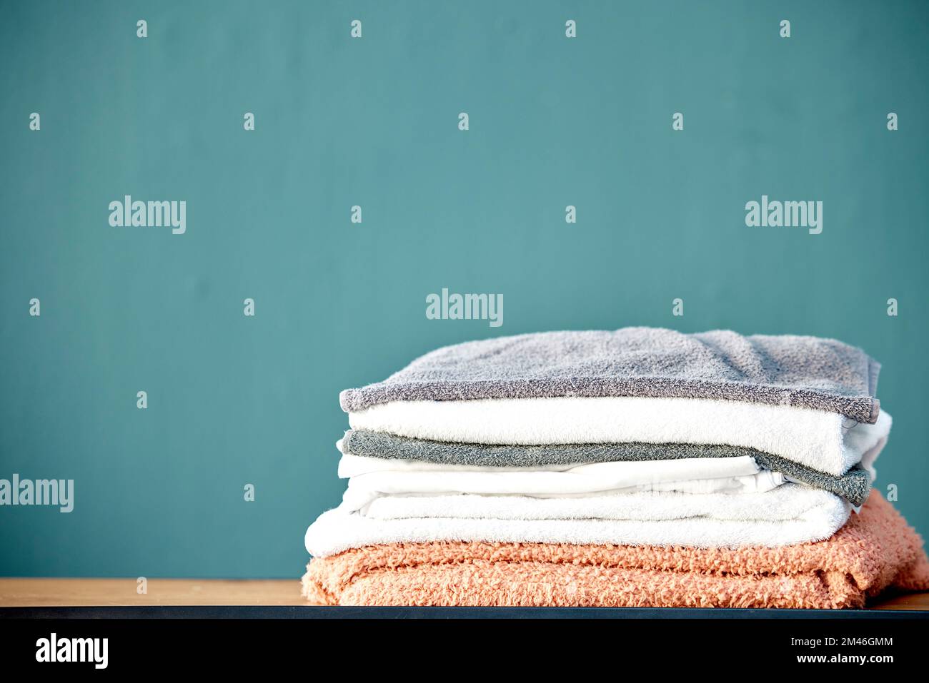 Bad, Wäsche und Handtuchstapel auf blauem Hintergrund für Reinigung, Waschen und Körperhygiene zu Hause. Stoff, Textilien und ein Haufen frischer, weicher und Stockfoto