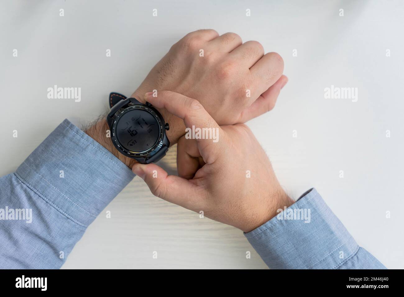 Business-, Technologie- und Mitarbeiterkonzept. Nahaufnahme von männlichen Händen, die die Smartwatch einstellen. Draufsicht Stockfoto