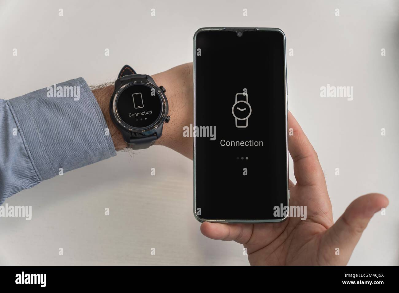 Ein Mann hält ein Smartphone und eine Smartwatch in der Hand. Kabellose Verbindung von Uhr und Mobiltelefon. Wi-Fi-Anschluss für Smartphone und Smartwatch Stockfoto