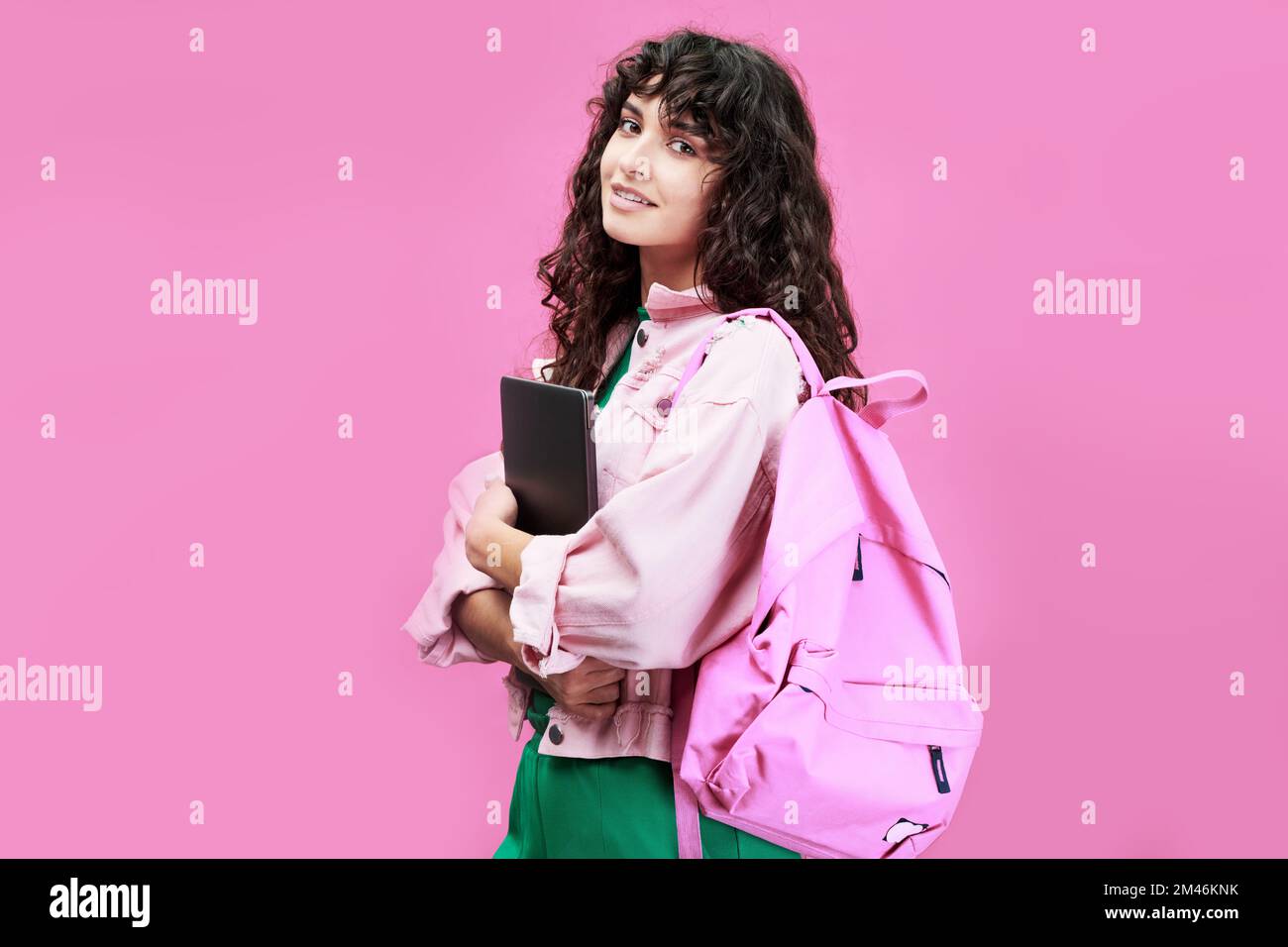 Schlaue Studentin an der Universität oder Highschool mit Jeansjacke, die vor der Kamera vor pinkfarbenem Hintergrund steht Stockfoto