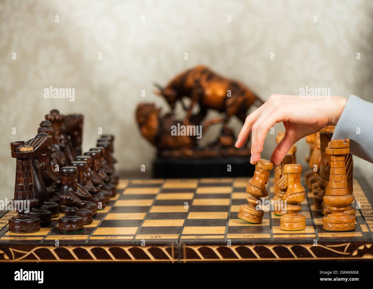 eine dame, die den ersten Schritt mit einem weißen Holzbauern im Schachspiel im alten Wohnzimmer macht Stockfoto