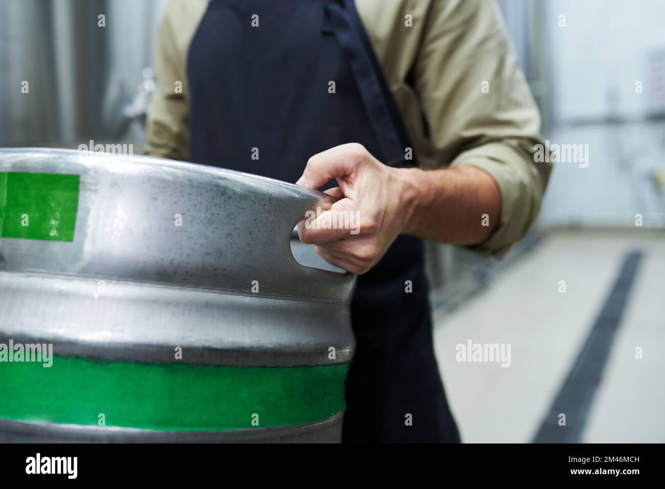 Zugeschnittenes Bild eines Arbeiters, der ein Fass mit Bier trägt Stockfoto