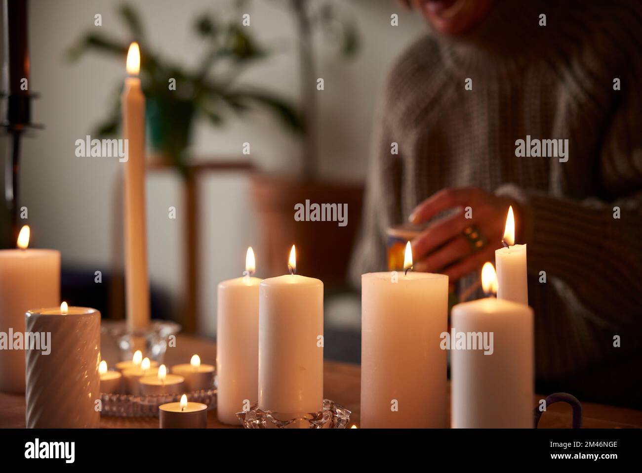 Eine Frau, die zu Hause mit Kerzen sitzt Stockfoto