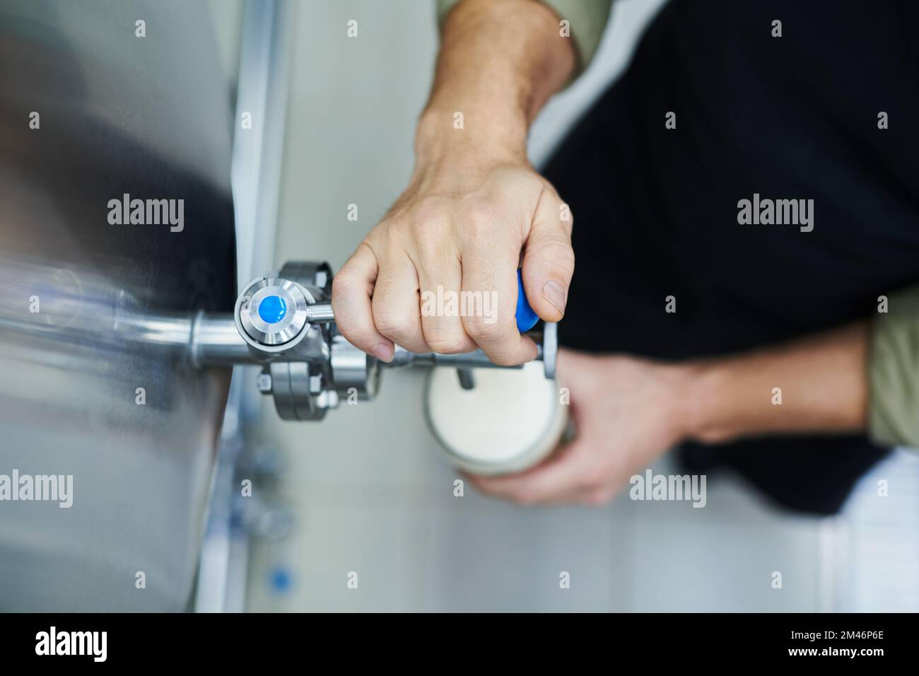 Nahaufnahme eines Brauereiarbeiters, der Bier aus dem Tank in großes Glas gießt Stockfoto