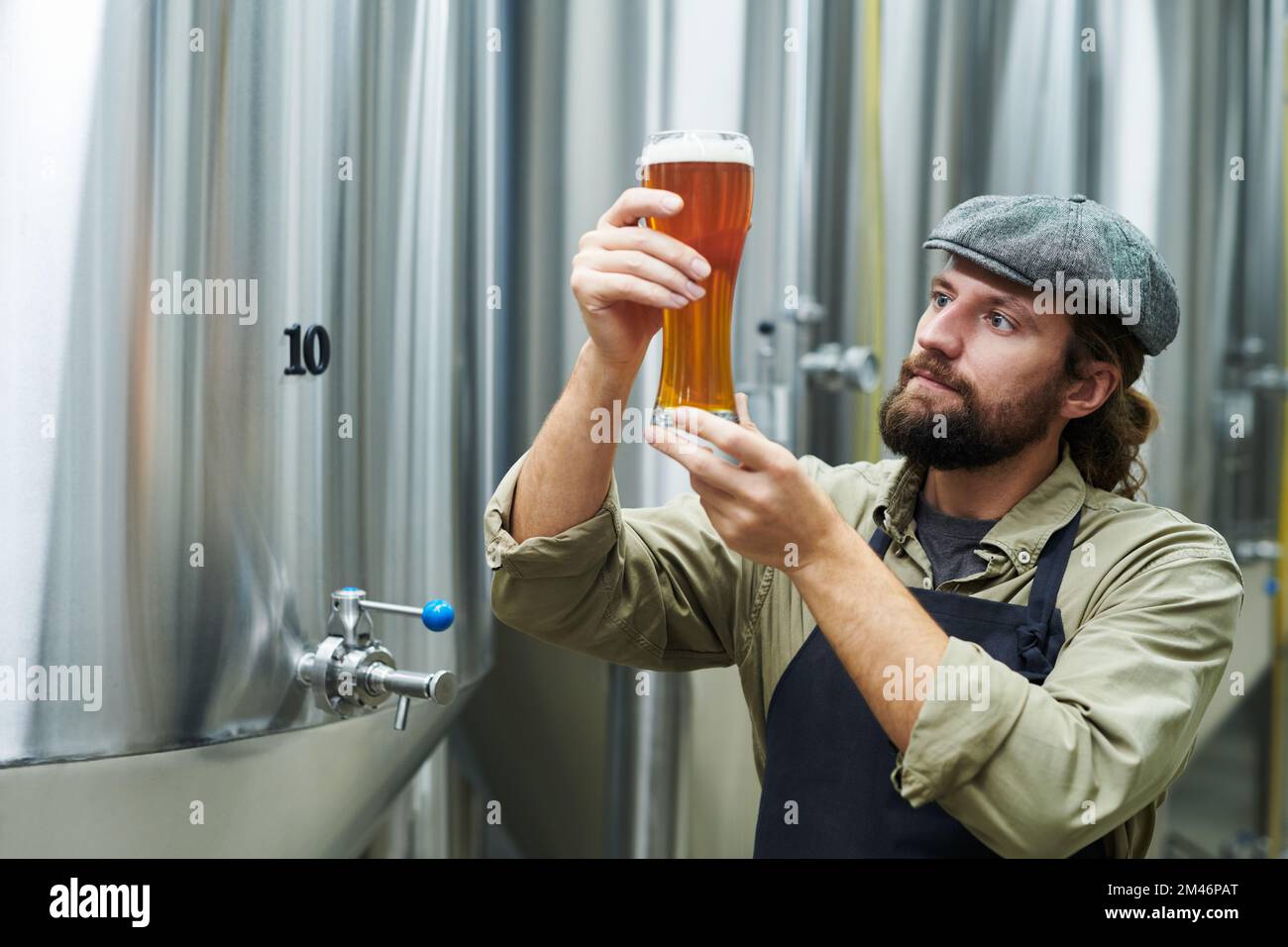 Der leidenschaftliche Brauereibesitzer schaute sich ein großes Glas Bier an und prüfte die Qualität des Getränks Stockfoto