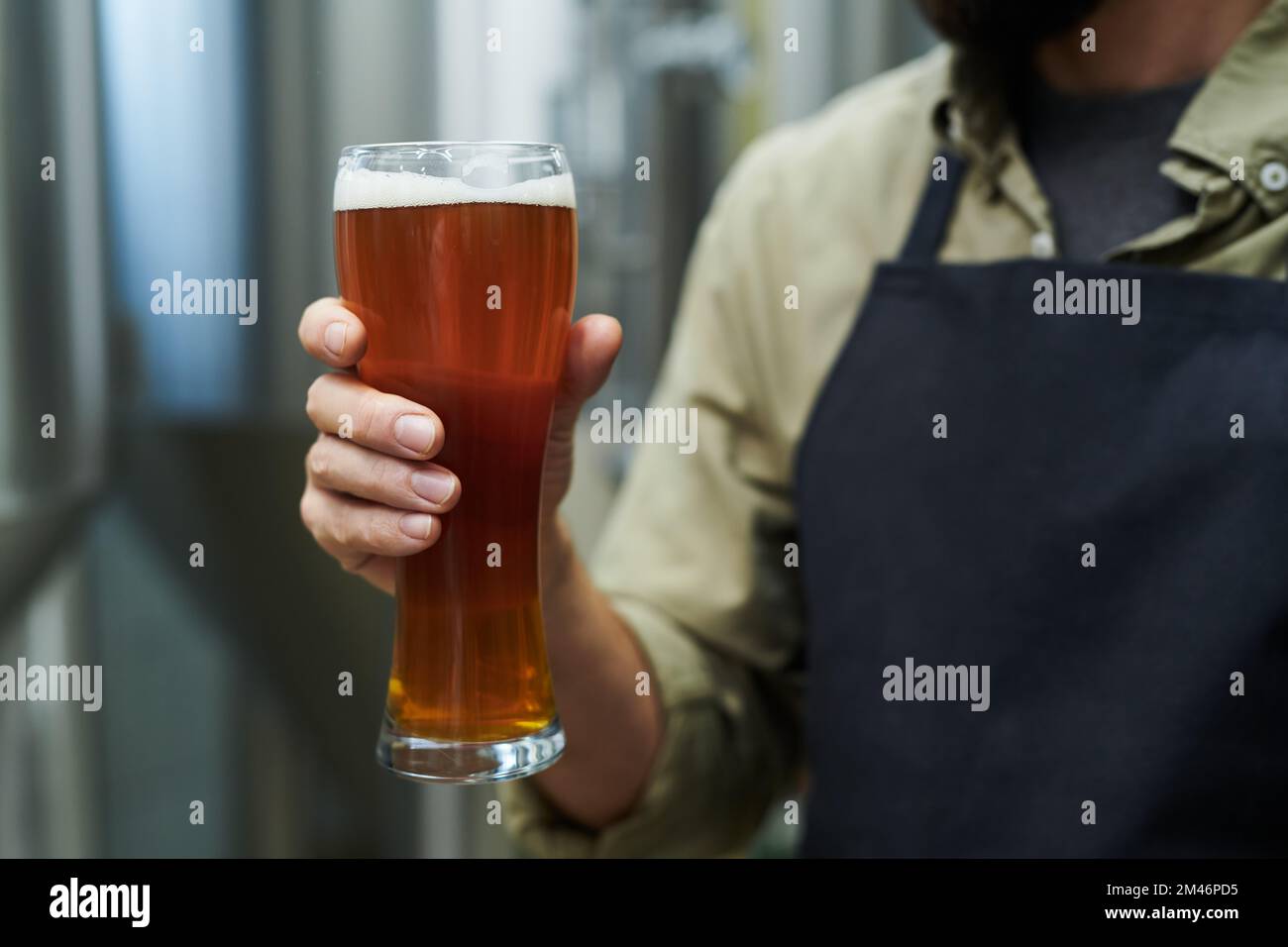 Arbeiter, der ein großes Glas Bier hält, das in einer Mikrobrauerei hergestellt wird Stockfoto