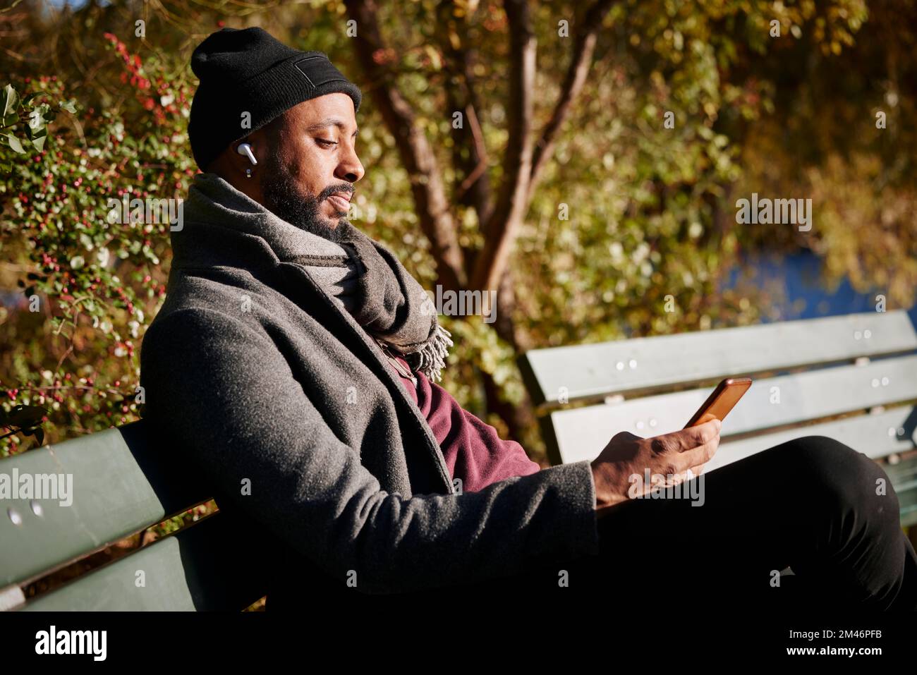 Mann sitzt auf einer Bank und telefoniert im Herbstpark Stockfoto