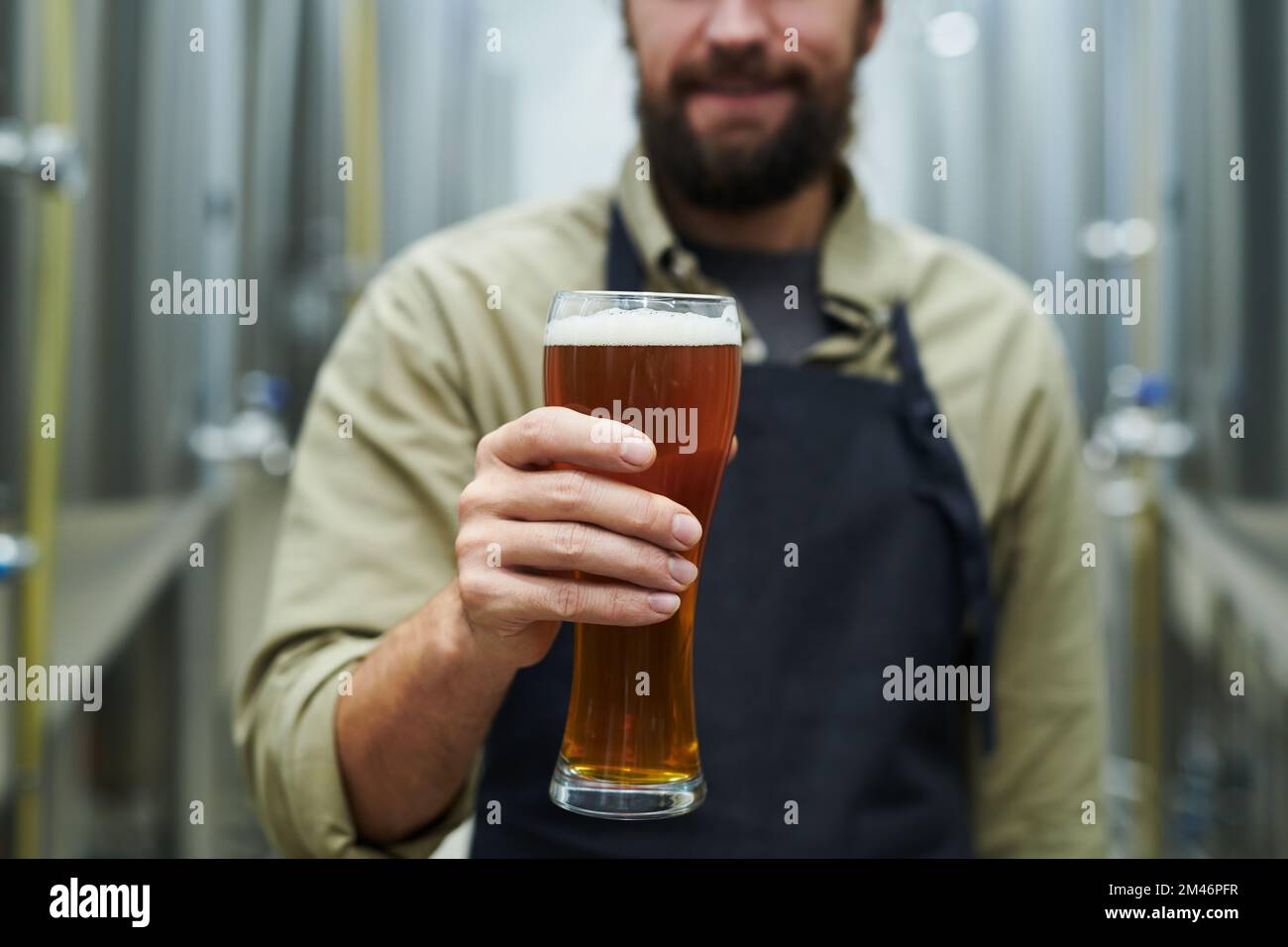 Abgeschnittenes Bild des Eigentümers einer Mikrobrauerei mit einem großen Glas Bier Stockfoto