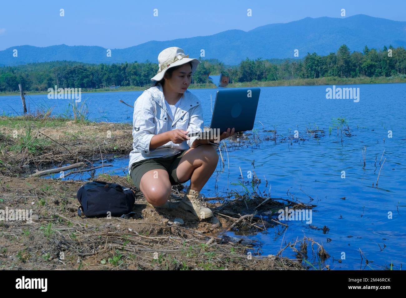 Umweltschützerin mit Laptop-Computer zur Erfassung von Krankheitserregern in natürlichem Wasser. Wasser- und Ökologiekonzept Stockfoto