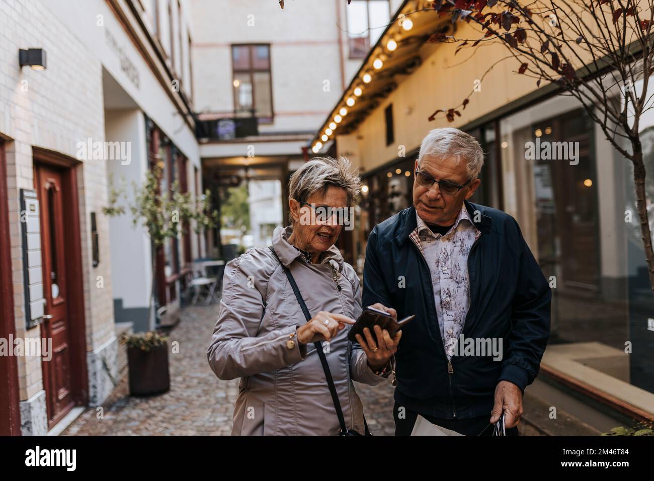 Seniorenpaar, das in der Stadt ein Smartphone benutzt Stockfoto Seniorenpaar, das in der Stadt ein Smartphone benutzt Stockfoto