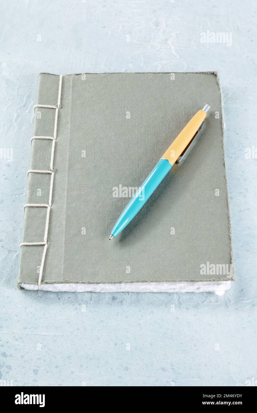 Ein Tagebuch. Ein handgefertigtes, genähtes Papiertagebuch mit einem Stift auf dem Schreibtisch, minimalistischer Stil Stockfoto