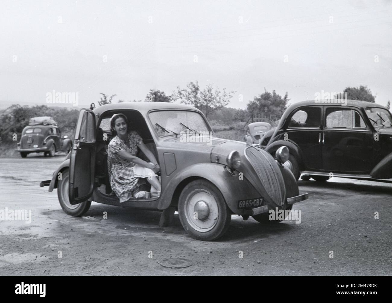 Junge Französin posiert in einem 5 2-türigen Saloon aus dem Vintage Simca, der zwischen 1936 und 1948 in Nanterre Frankreich hergestellt wurde. Das französisch-italienische Auto war identisch mit dem Fiat 500 Topolina. 1951 fotografiert Stockfoto