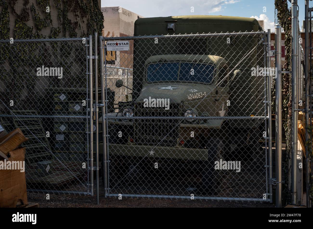 Ein alter Militärwagen aus dem Zweiten Weltkrieg, der in einer Gasse hinter einem Metallzaun geparkt ist. gmc Cckw Stockfoto