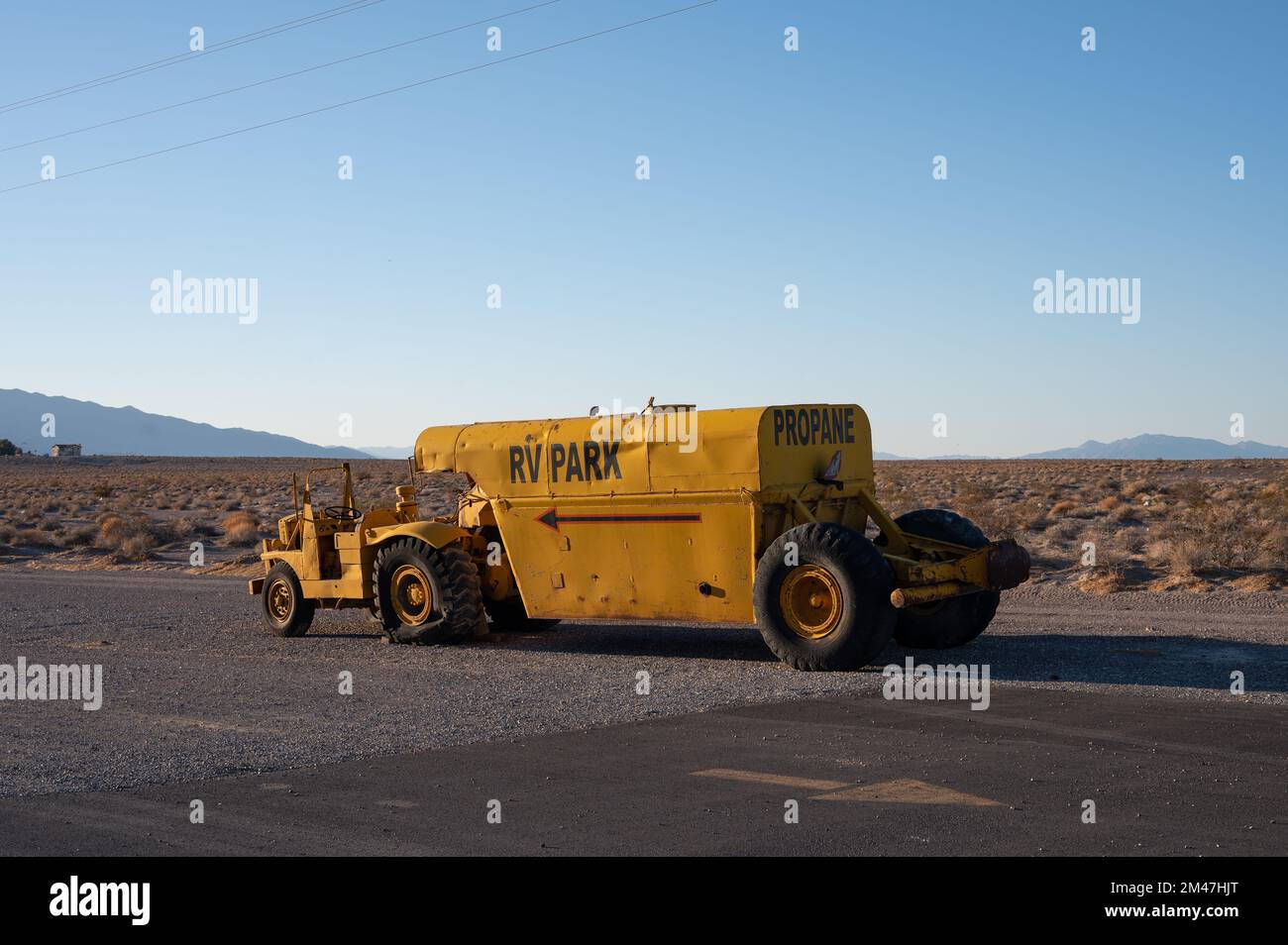 Gelber Traktor, der einen Anhänger mit Propantank transportiert. Caterpillar Baureihe DX10 1N 4x2. Ist verlassen Stockfoto