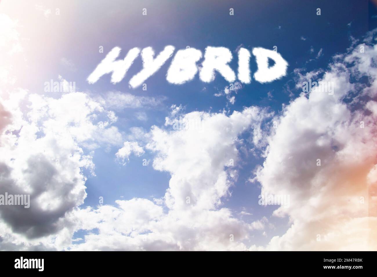 Hybrid. Text von Wolken am Himmel in hellem Sonnenlicht. Stockfoto