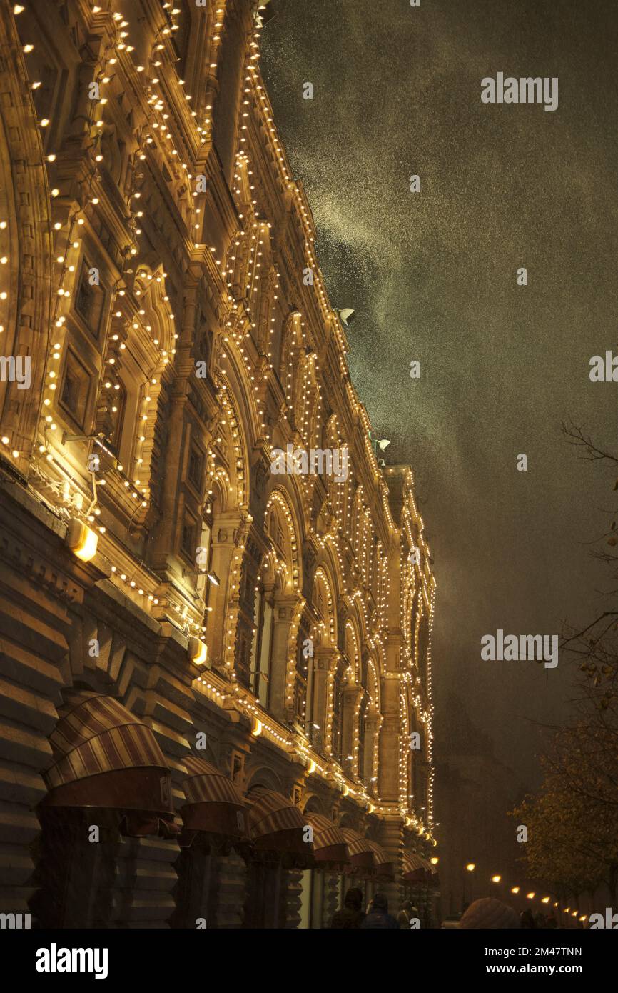 Beleuchtete Fassade des KAUGUMMI-Kaufhauses bei einem plötzlichen Schneesturm in der Nacht. Moskau, Russland. Stockfoto