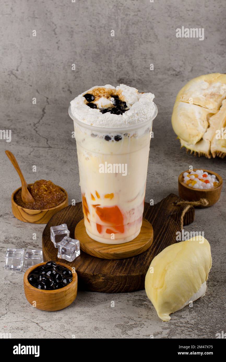 Boba- oder Tapiokapperlen sind taiwanischer Seifenmilchtee in Plastikbecher mit Duriangeschmack auf Texturhintergrund, Sommererfrischung. Stockfoto