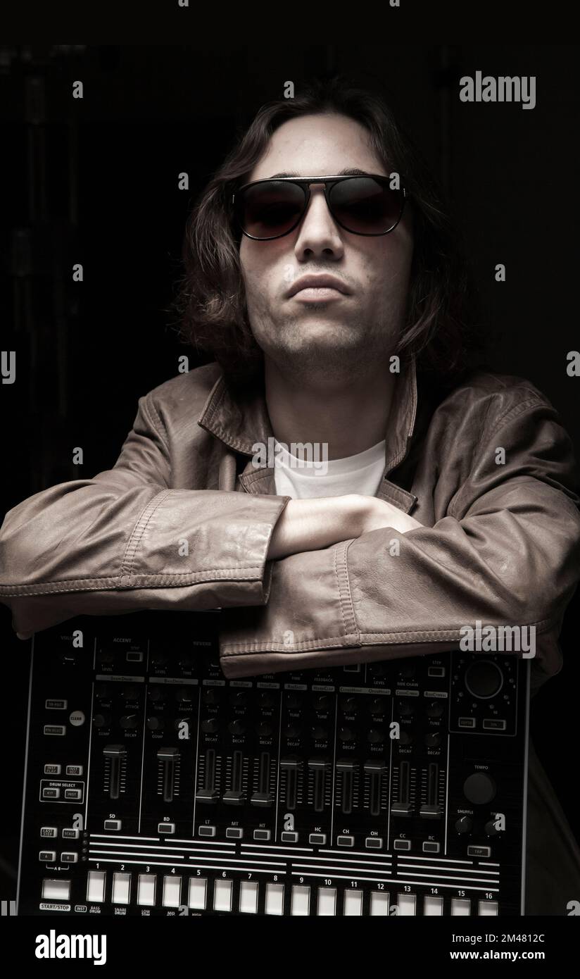 Porträt eines Hip-Hop-Musikers in Studiobeleuchtung mit Beat-Maschine. Schwarzer Hintergrund, Stockfoto