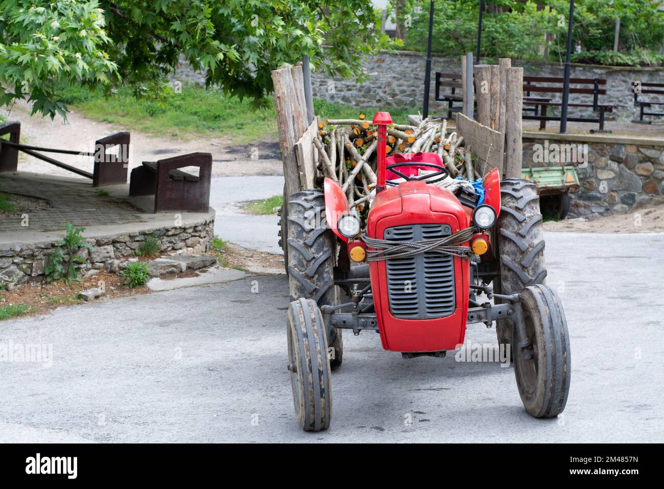 Alter roter Traktor, der Holz transportiert Stockfoto