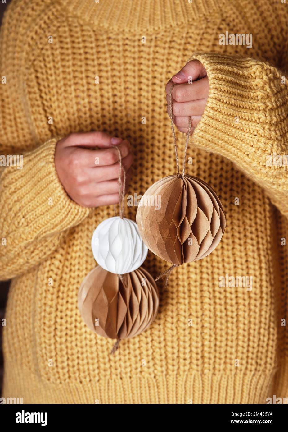 Handgemachte weihnachtliche Wabenkugeln aus weißem und braunem Kaffeefilter in Frauenhänden. Skandinavisches Handwerkspapier Konzept. Selektiver Fokus. Stockfoto