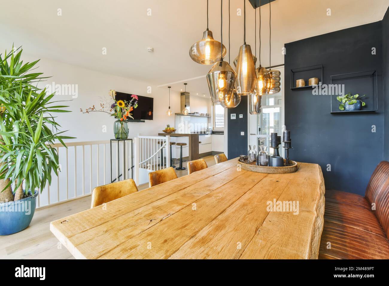 Ein Esszimmer mit einem Holztisch und einigen Pflanzen in Töpfen an der Wand neben der Küche ist dunkelblau Stockfoto