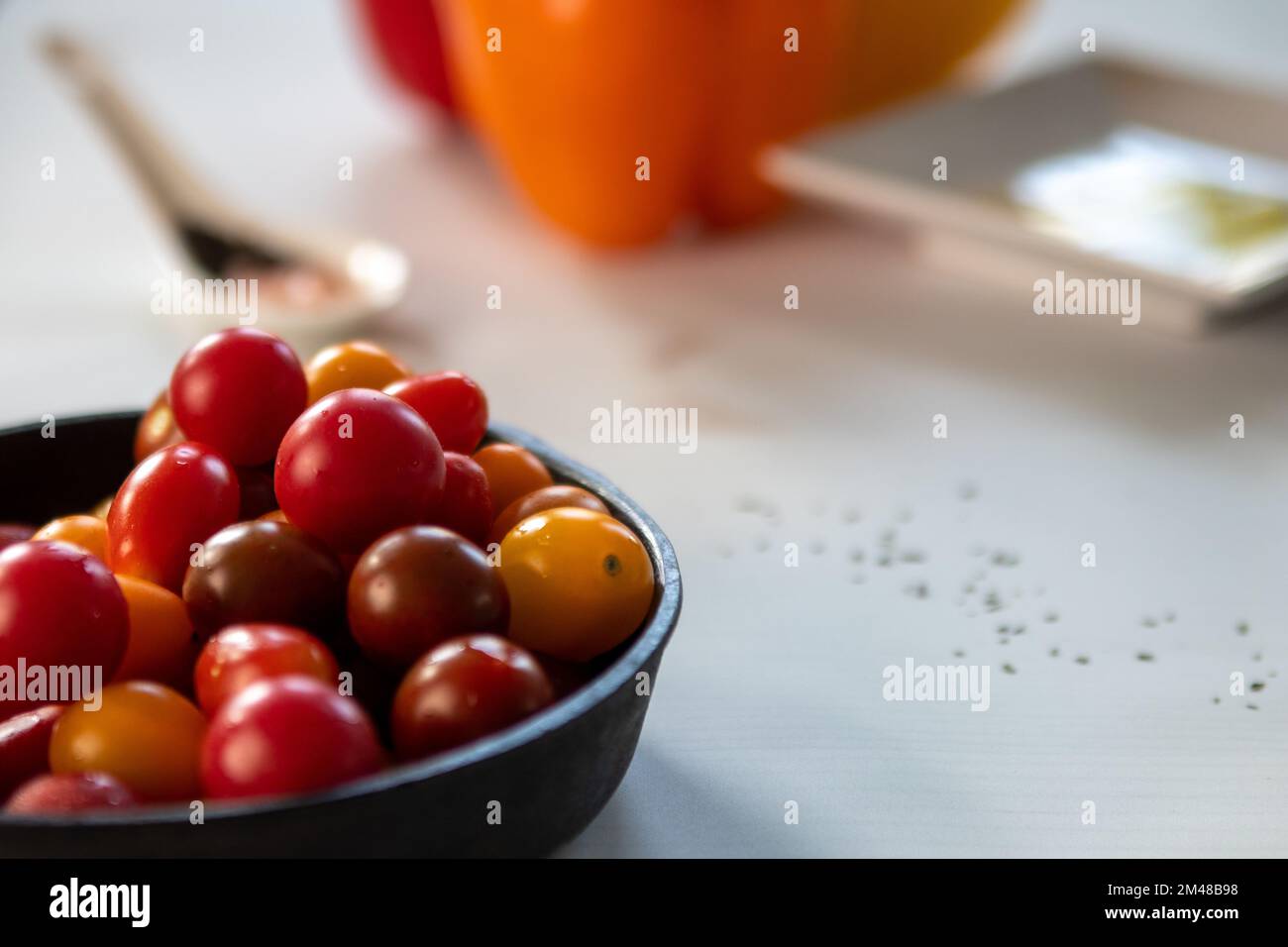 Kirschtomaten in gut gebrauchtem Gusseisen mit Salz, Pfefferöl und rotem Paprika. Stockfoto