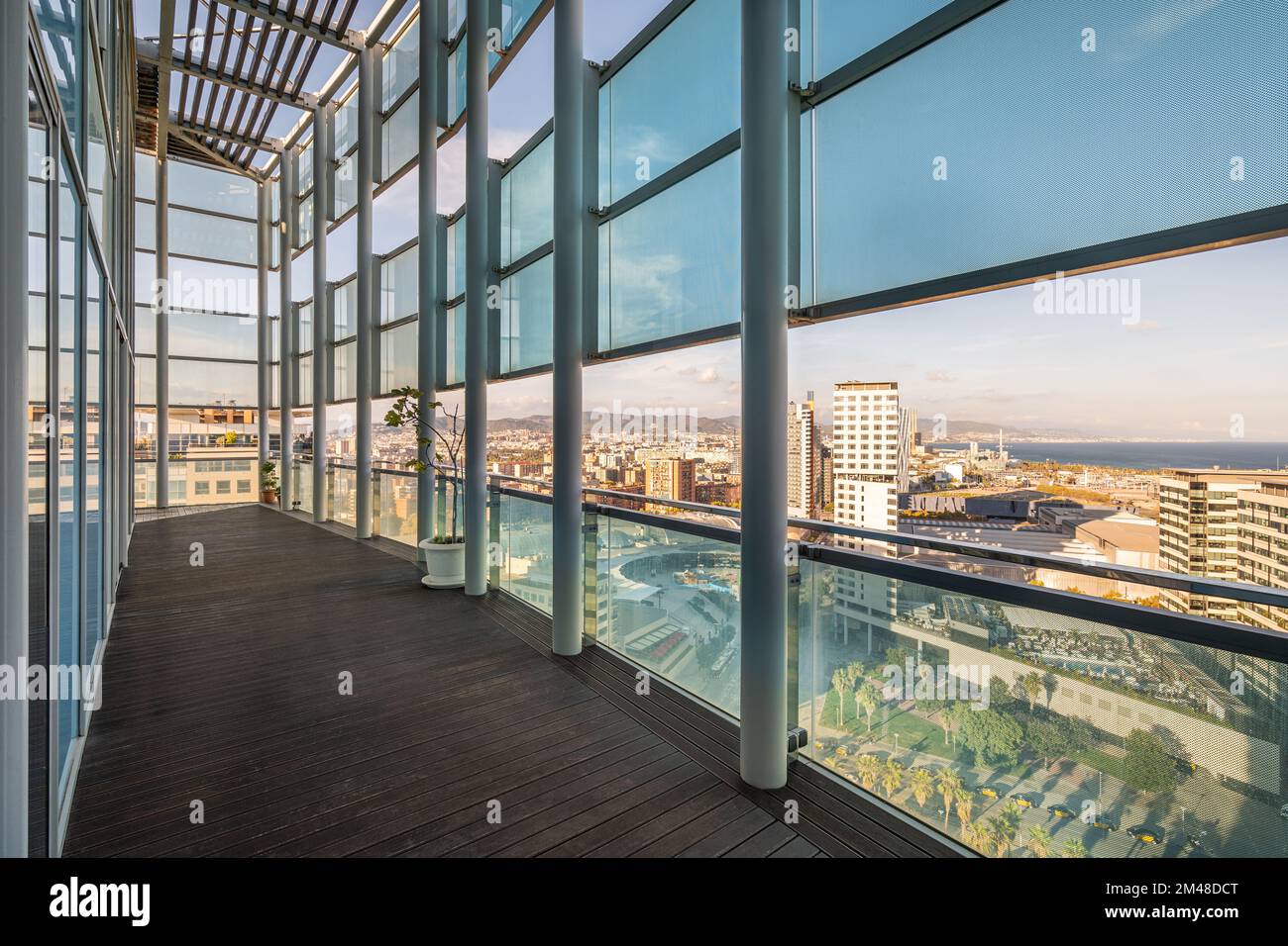 Lange geräumige Terrasse in einem Hochhaus mit Zaun und Dach aus Metallbalken aus starkem, stoßfestem Glas, das vor direkter Sonneneinstrahlung geschützt ist Stockfoto