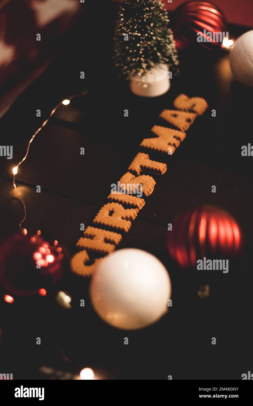 Lebkuchen-Worte Frohe Weihnachten auf einem alten schwarzen Tisch mit Weihnachtsdekorationen Stockfoto