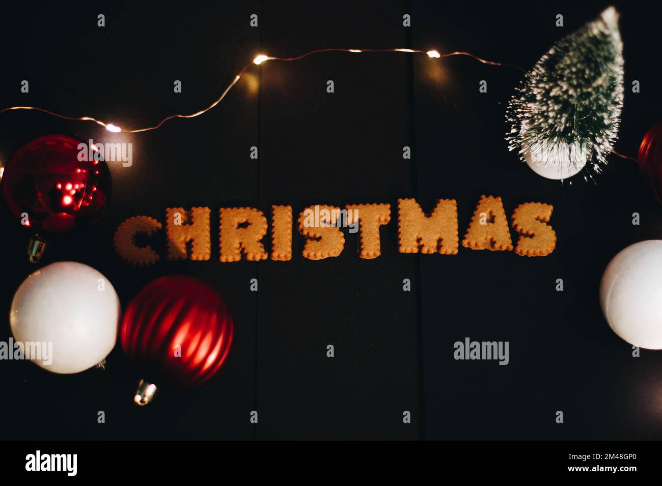 Lebkuchen-Worte Frohe Weihnachten auf einem alten schwarzen Tisch mit Weihnachtsdekorationen Stockfoto