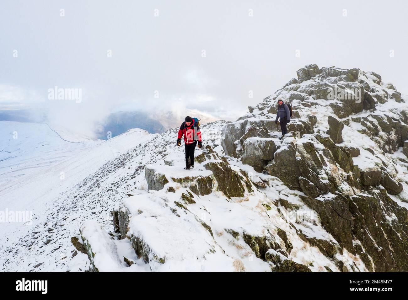 Bergsteiger auf einer Winterwanderung am Striding Edge auf Helvellyn im Lake District National Park, Cumbria, Großbritannien Stockfoto