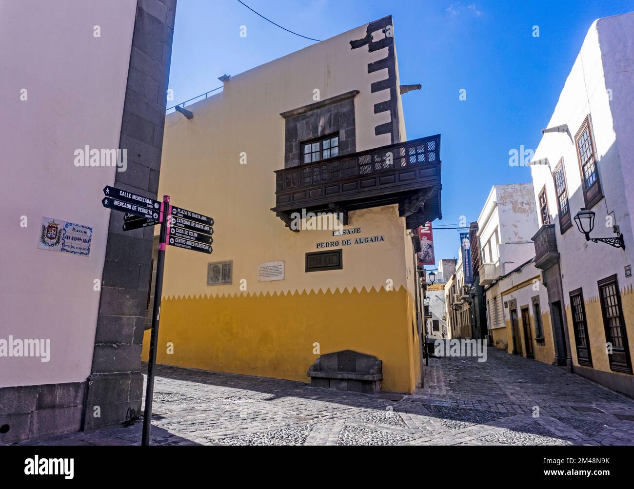 Eine Seitenstraße in der Altstadt von Palmas, Gran Canaria mit einem Straßenschild, das Wegbeschreibungen zum Plaza de Santa Anna Square, zur Kathedrale von Santa Ana usw. zeigt Stockfoto