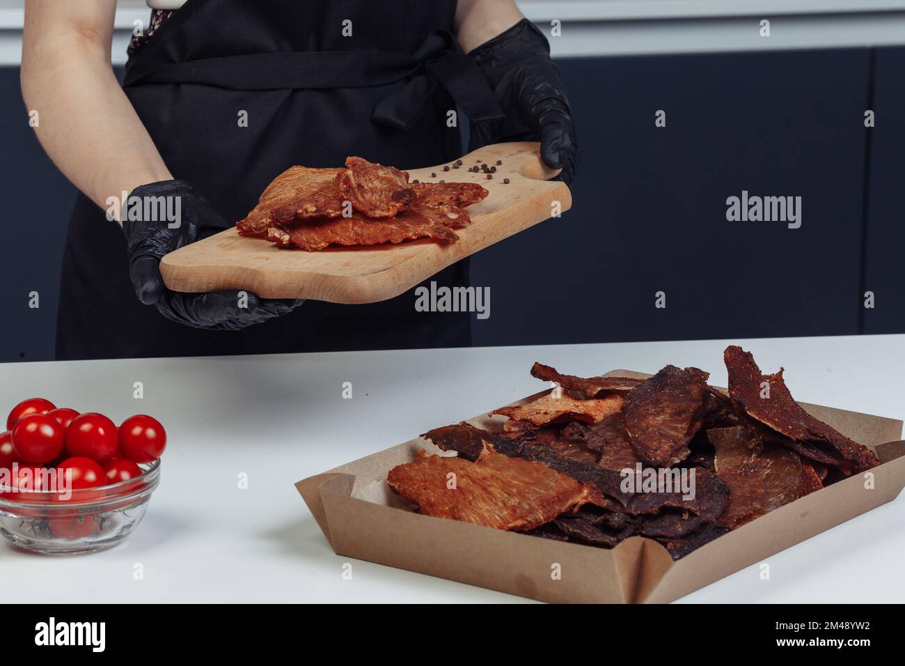 Ein Typ packt getrocknetes Fleisch in Papierkartons mit schwarzen Handschuhen. Hochwertiges Foto Stockfoto