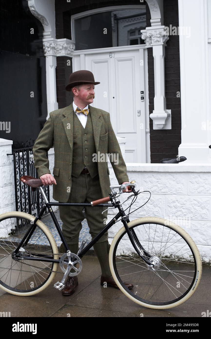London ein eleganter Mann, der neben dem Pashley Guvnor Fahrrad steht und Anzug mit Melone und Fliege trägt. Stockfoto